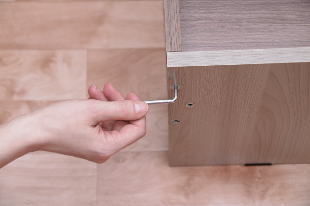 一个白人女孩用钥匙拧紧了家具上的一个螺丝钉。特写镜头。图片下载