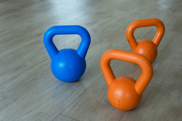 蓝色橙色壶铃举重锻炼和体育运动在健身房木地板的背景图片下载
