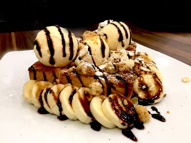 蜂蜜吐司与巧克力，香蕉，核桃和枫糖浆滴在木制背景。图片下载