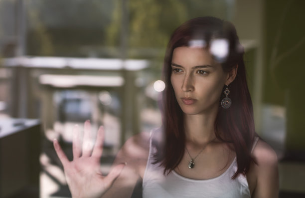 年轻迷人的女子望着窗外沉思图片下载