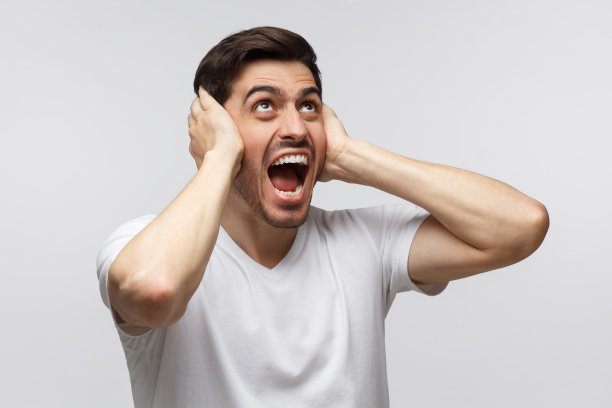 年轻的尖叫愤怒的男子从上面向吵闹的邻居大喊，噪音的压力，紧闭耳朵的双手图片下载