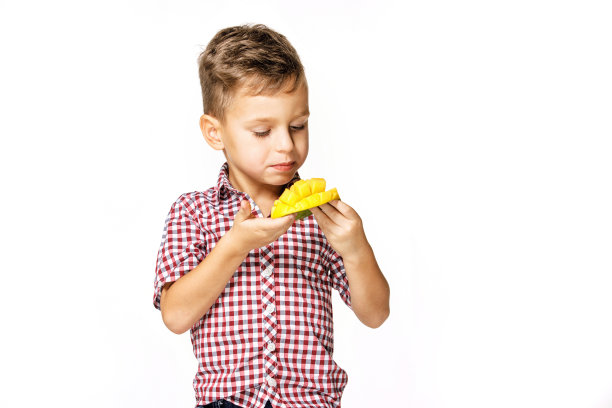 穿着红衬衫的英俊男孩正在吃芒果图片下载