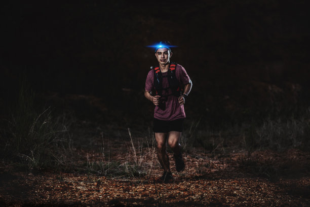 夜间在岩石路上奔跑的越野跑者图片下载