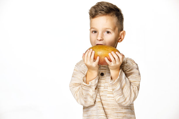 英俊的小男孩拿着一个芒果图片下载