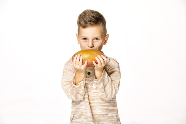 英俊的小男孩拿着一个芒果图片下载