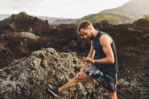年轻人伸伸懒腰，然后跑着看手机。使用耳机同步音乐。图片下载