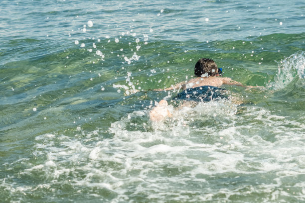 13岁的男孩在海浪中游泳和放松。家庭暑假的概念图片下载