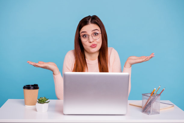 近距离的照片美丽的她，她的狐狸精女士的手，手臂举起的一边，不感兴趣的面部表情笔记本，咖啡杯，桌子，桌子，戴眼镜，休闲的，柔和的，暖和的套衫，孤立的亮蓝色背景图片下载