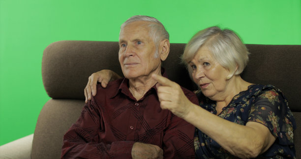 老男人和老女人一起坐在沙发上看电视。色度键图片下载