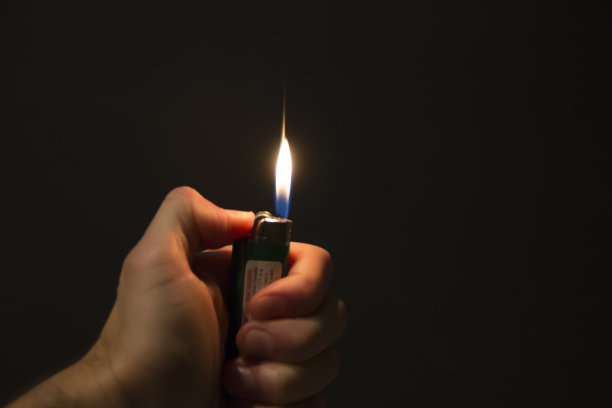 在黑暗中拿着点燃的打火机图片下载