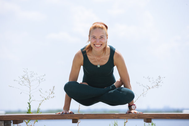 图片年轻的健身女士在户外的海滩做瑜伽伸展运动。图片下载