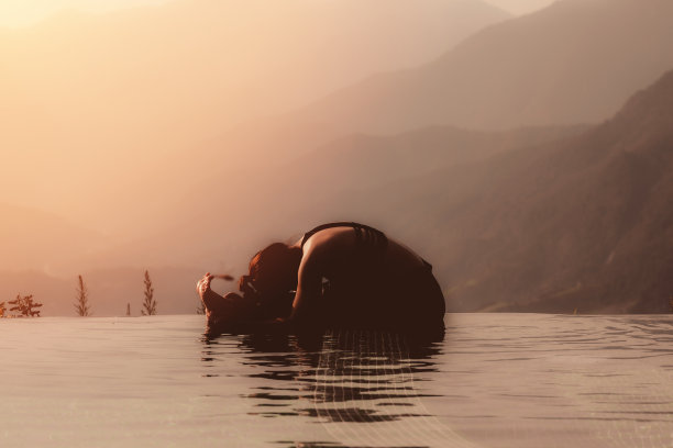 清晨，在美丽的自然景色前，女性坐在山顶上方的泳池上练习瑜伽，感觉如此舒适和放松的瑜伽在假日，暖色调图片下载