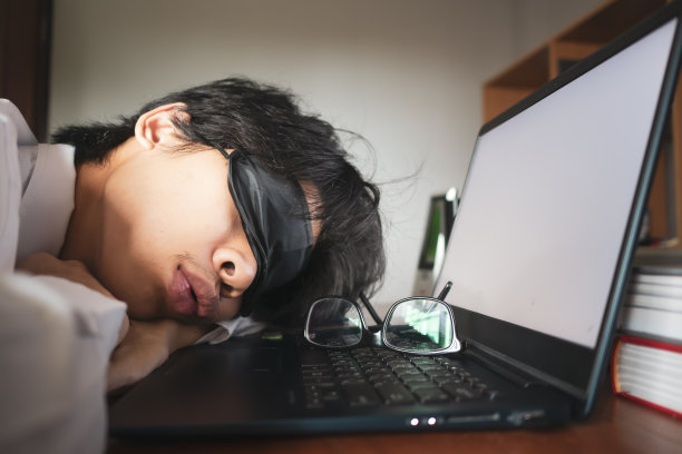 在笔记本电脑前睡觉的年轻人。图片下载