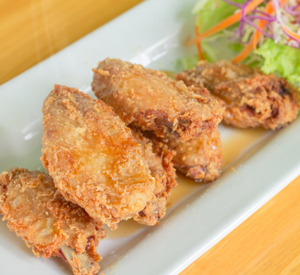 炸鸡、鱼露、生菜、胡萝卜、花椰菜，放在一张木桌上的白盘子里图片下载