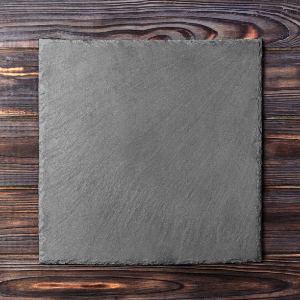 方形盘子放在桌上。木背景上的黑色盘子。本空间图片下载