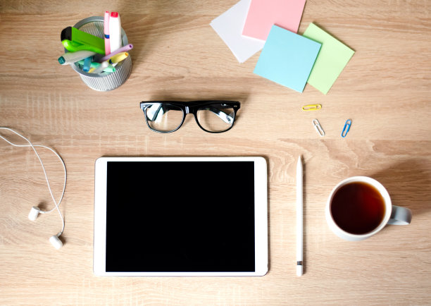 木制的桌子。带黑框眼镜的白色平板电脑。一杯茶。图片下载