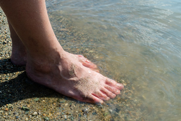 女人的脚在海岸线的海滩上，温暖的夏日图片下载