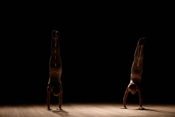 柔韧性强的孩子，漂亮的小体操女孩在做体操，黑色的背景。运动，训练，伸展，积极的生活方式概念。图片下载