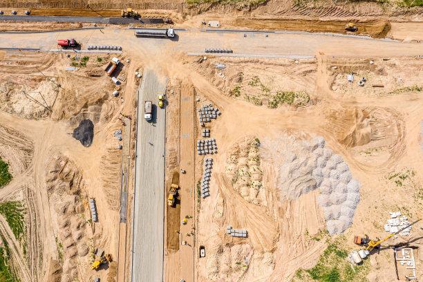 建筑工地鸟瞰图。压路机、挖掘机和自卸卡车为筑路铺路图片下载