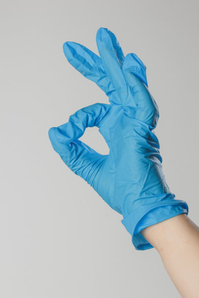 横幅。一只戴着医用乳胶白手套的手，在蓝色背景下显示一个OK手势。医学背景。图片下载