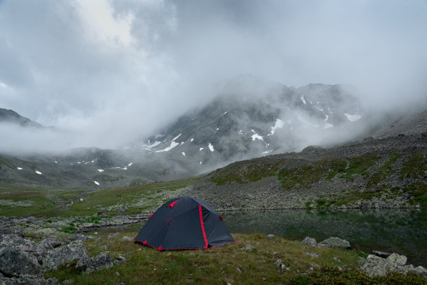 旅游帐篷附近的山湖背景在扎尔考什山薄雾中的低云图片下载
