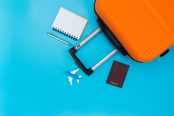 平铺橙色手提箱与旅行配件在软蓝色背景。旅游、夏季和假期概念图片下载