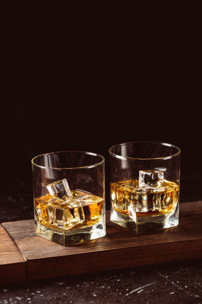 两杯威士忌加冰块，放在木板上。图片下载