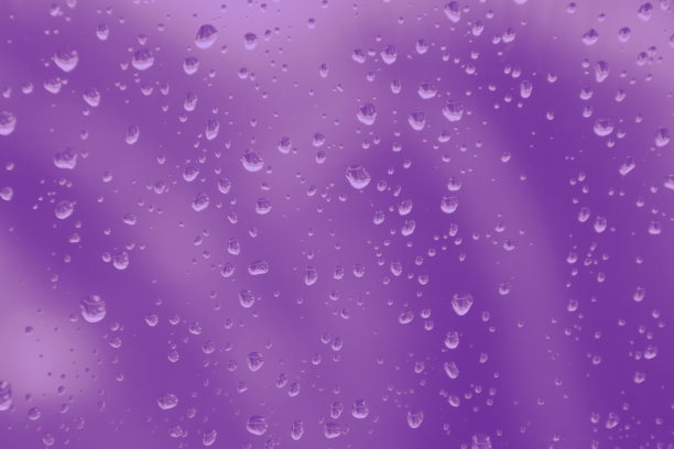 雨滴落在窗户玻璃上，紫色的色调模糊了背景图片下载