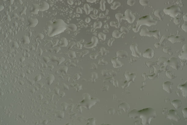 特写微距照片的水滴捕捉玻璃窗户与黑暗的背景俯瞰城市街道。图片下载