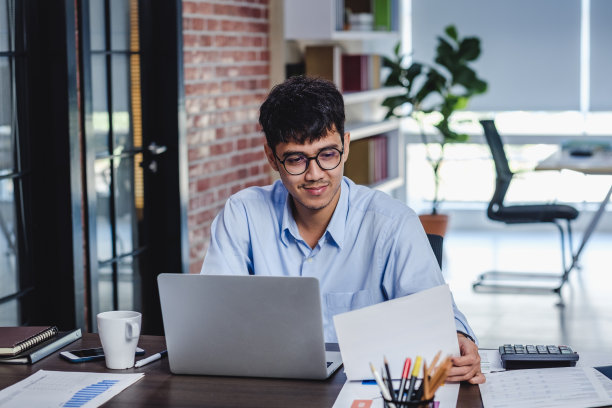 亚洲商人在办公室用笔记本电脑和文件工作。数字工作流在线商务生活理念。图片下载