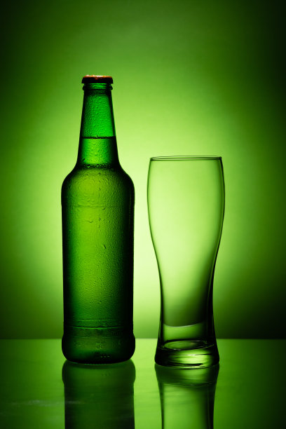 一瓶冷凝的啤酒，空杯子图片下载