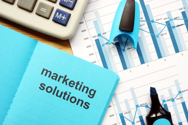 写便条展示营销解决方案。商业图片展示营销解决方案。课文写在蓝色的笔记本上。图在纸上，标记，木背景上的照片。图片下载