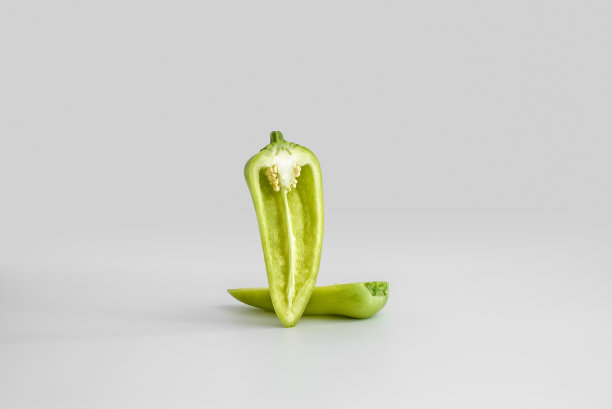半荚新鲜多汁的绿色甜椒在统一的白光背景下飞舞。最小的概念，复制空间。健康饮食的理念图片下载