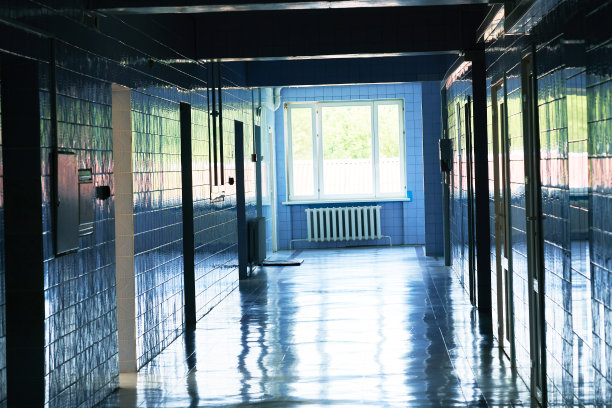 明亮的蓝色灯光下模糊不清的医院走廊照片。白色地板与冷色调与光线隧道中间的画面。图片下载