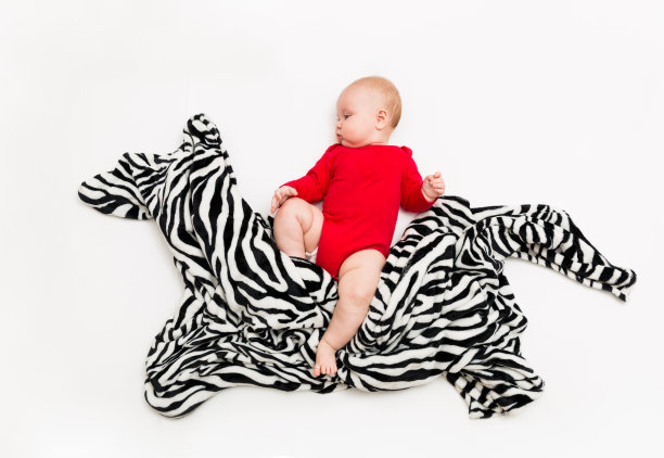 有趣可爱的婴儿坐在玩具马或斑马和微笑图片下载