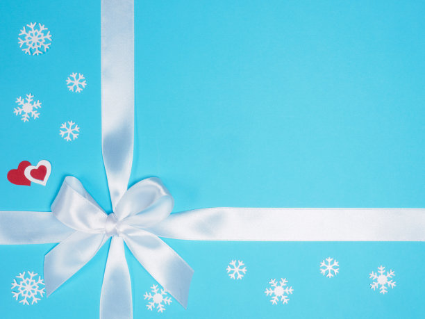 白色的蝴蝶结，雪花，蓝色背景上的两颗心。圣诞节和新年的概念图片下载