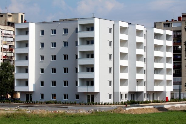 新的六层公寓楼周围是新种植的柏树和绿草图片下载