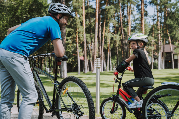 可爱的小女孩在骑自行车时与她的父亲交谈图片下载