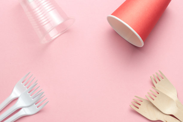 环保和塑料厨具模板或框架。木制的勺子和叉子在粉红色的珊瑚背景。图片下载