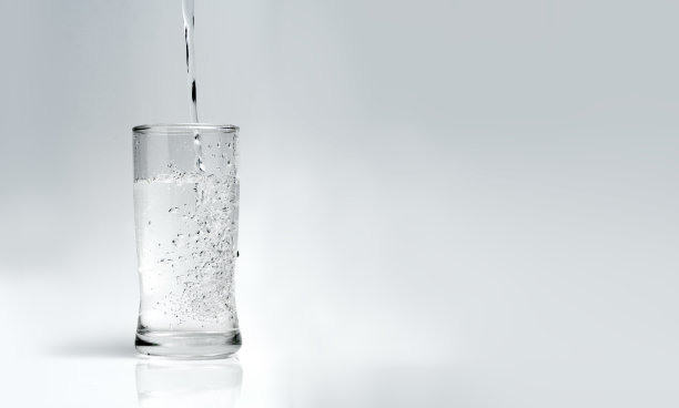 将水倒入白色背景的玻璃杯中图片下载