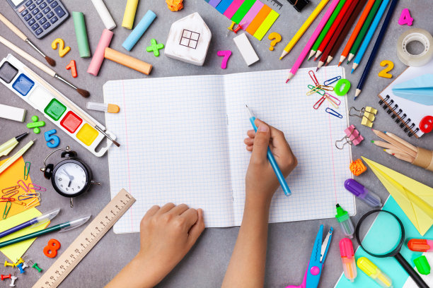 一套用品和文具与学生手写在空笔记本俯视图。教育、学习、返校理念。图片下载
