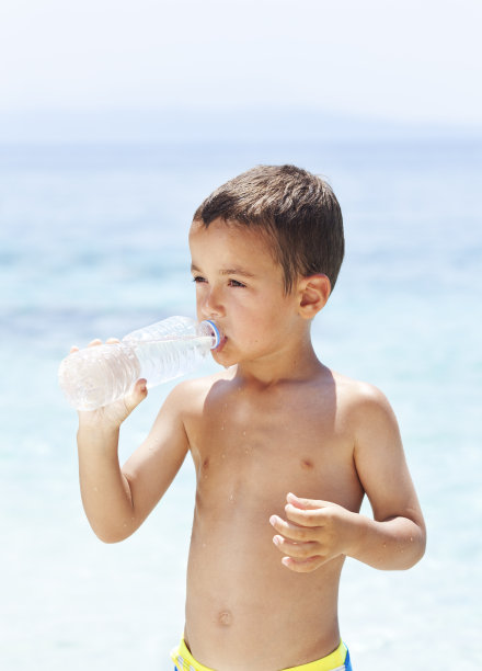 男孩在海滩上喝水图片下载