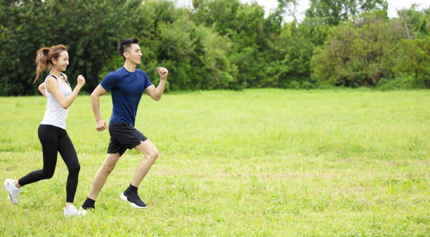 年轻夫妇在草地上跑步的侧视图图片下载