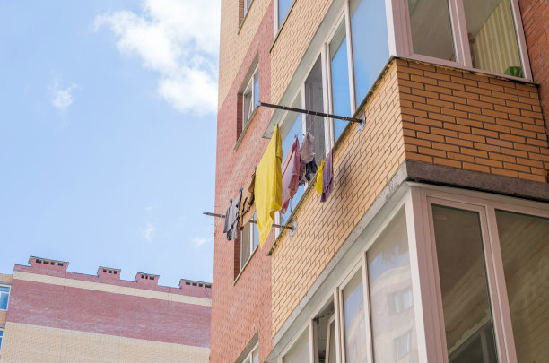 在一个阳光明媚，炎热的夏天，在公寓大楼的阳台上洗衣服和晾晒衣服。有选择性的重点。图片下载