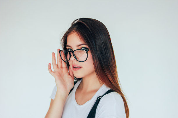 美丽体贴的女孩戴着眼镜，黑色长发，白色t恤孤立在白色背景图片下载