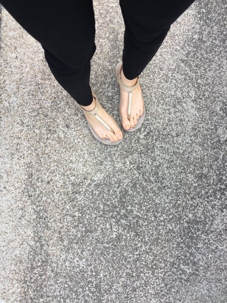 从上面看脚和腿。在混凝土背景上的时尚米色鞋子的脚自拍，俯视图。图片下载