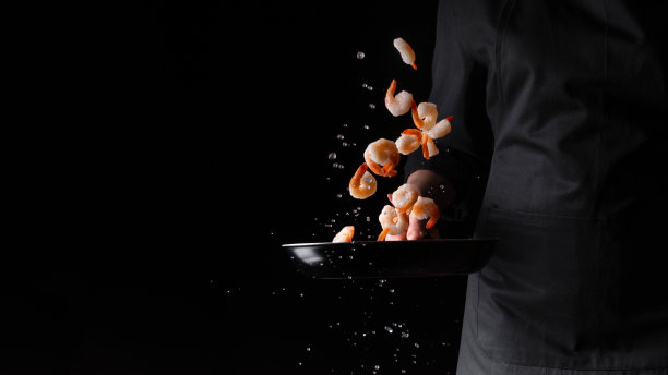 海鲜，厨师在煎锅里准备虾，烤。以黑色为背景进行设计，菜单、餐厅、东方料理、健康食品。水平的照片,横幅图片下载