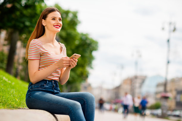简介侧面照片迷人的女孩与狐狸姜头发红色润发膏持有现代科技看着坐在城市户外的人行道上图片下载