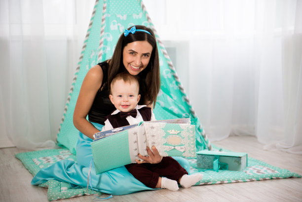 美丽的女人和她的小儿子在玩和微笑，在蓝色的背景。图片下载