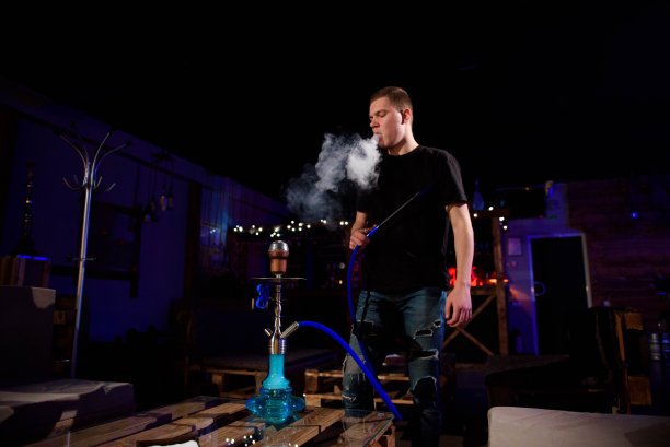 男人使水烟。现代水烟与椰子木炭放松和水烟。图片下载